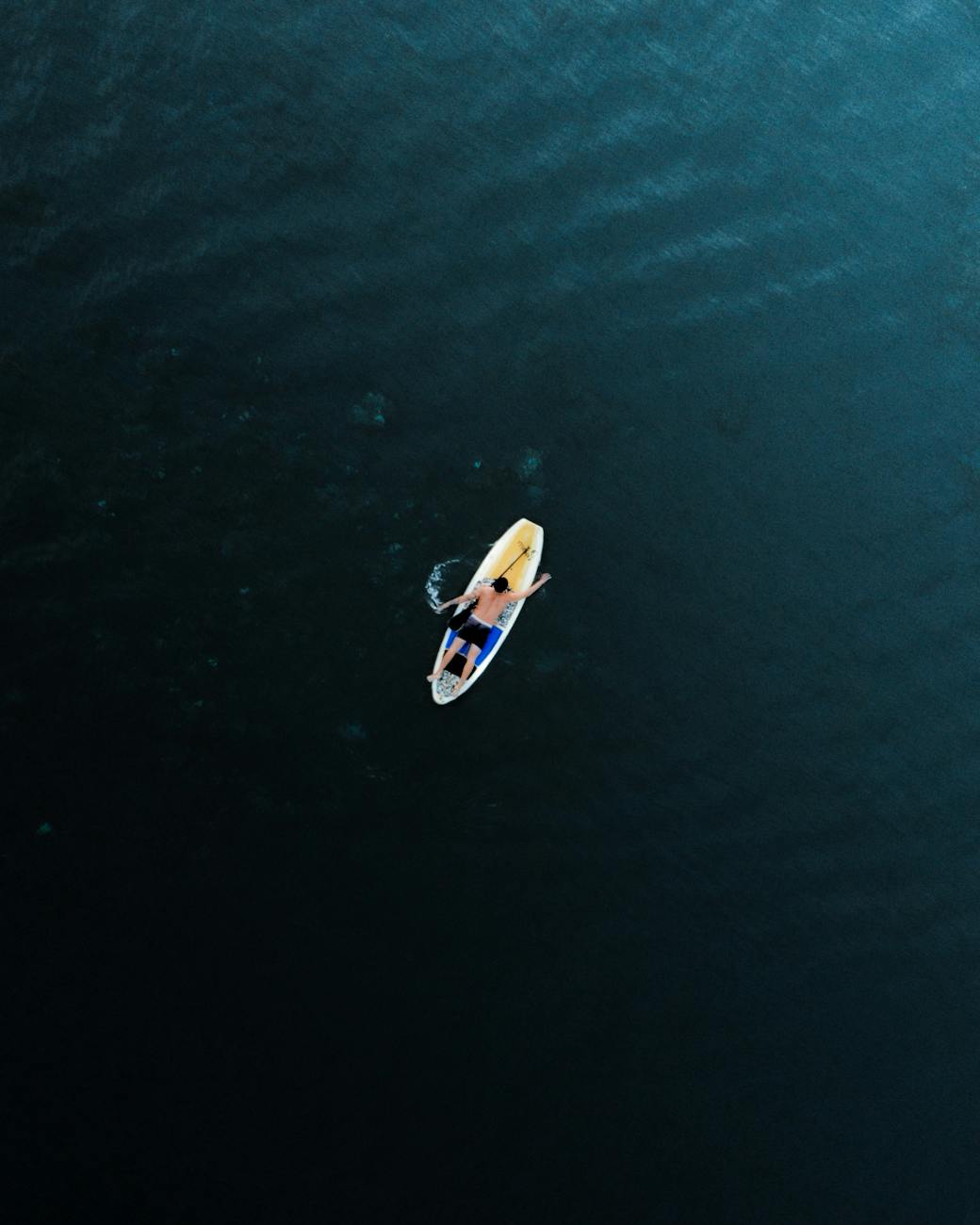 man lying on paddleboard in sea