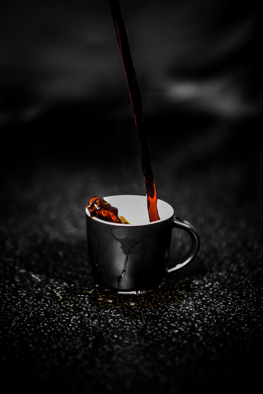 brown liquid pouring on black and white ceramic mug selective color photography