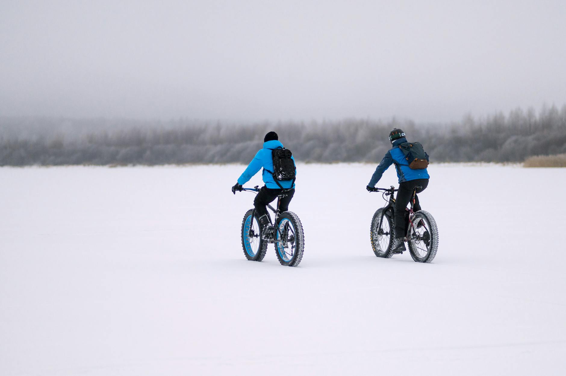 people riding bikes in snow in winter countryside