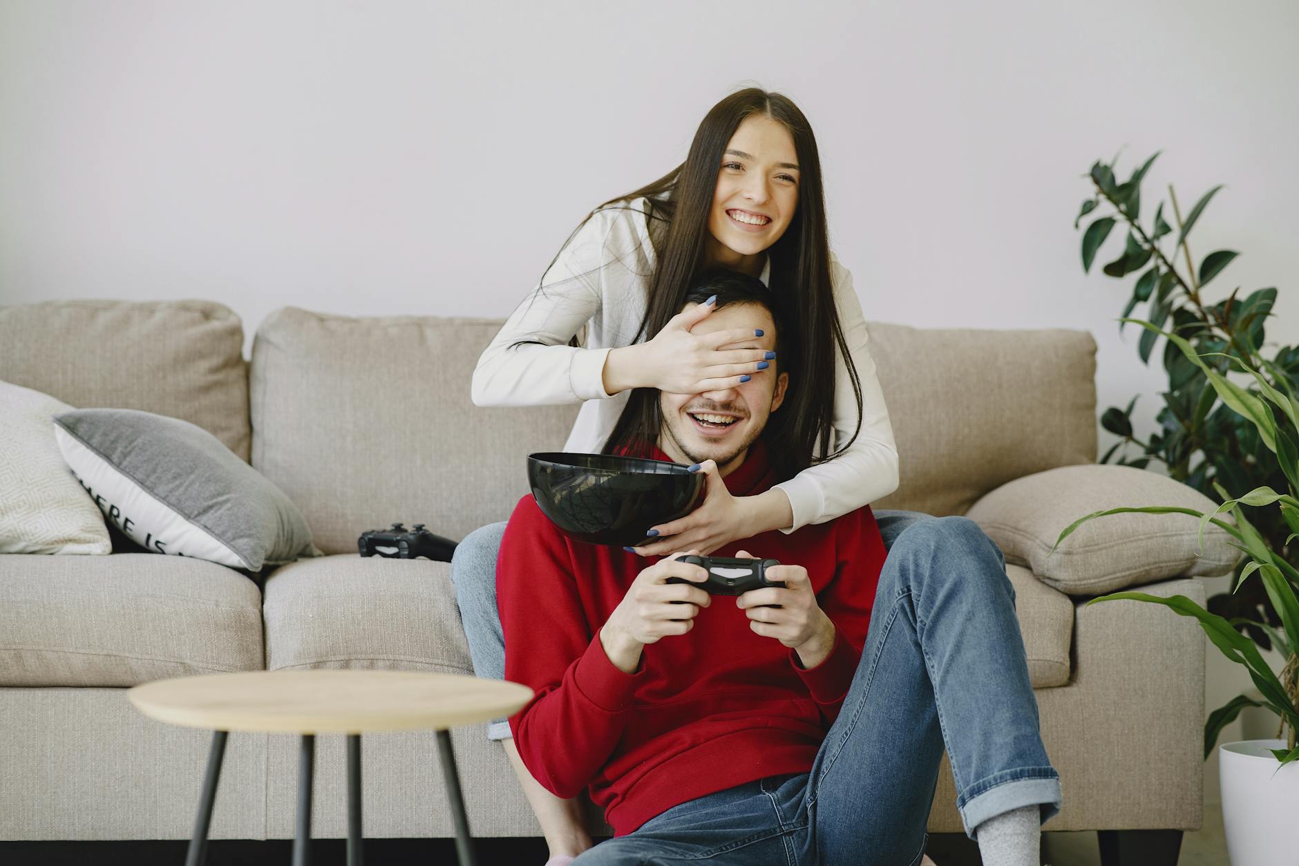 woman covering partners eyes with hand while playing game console