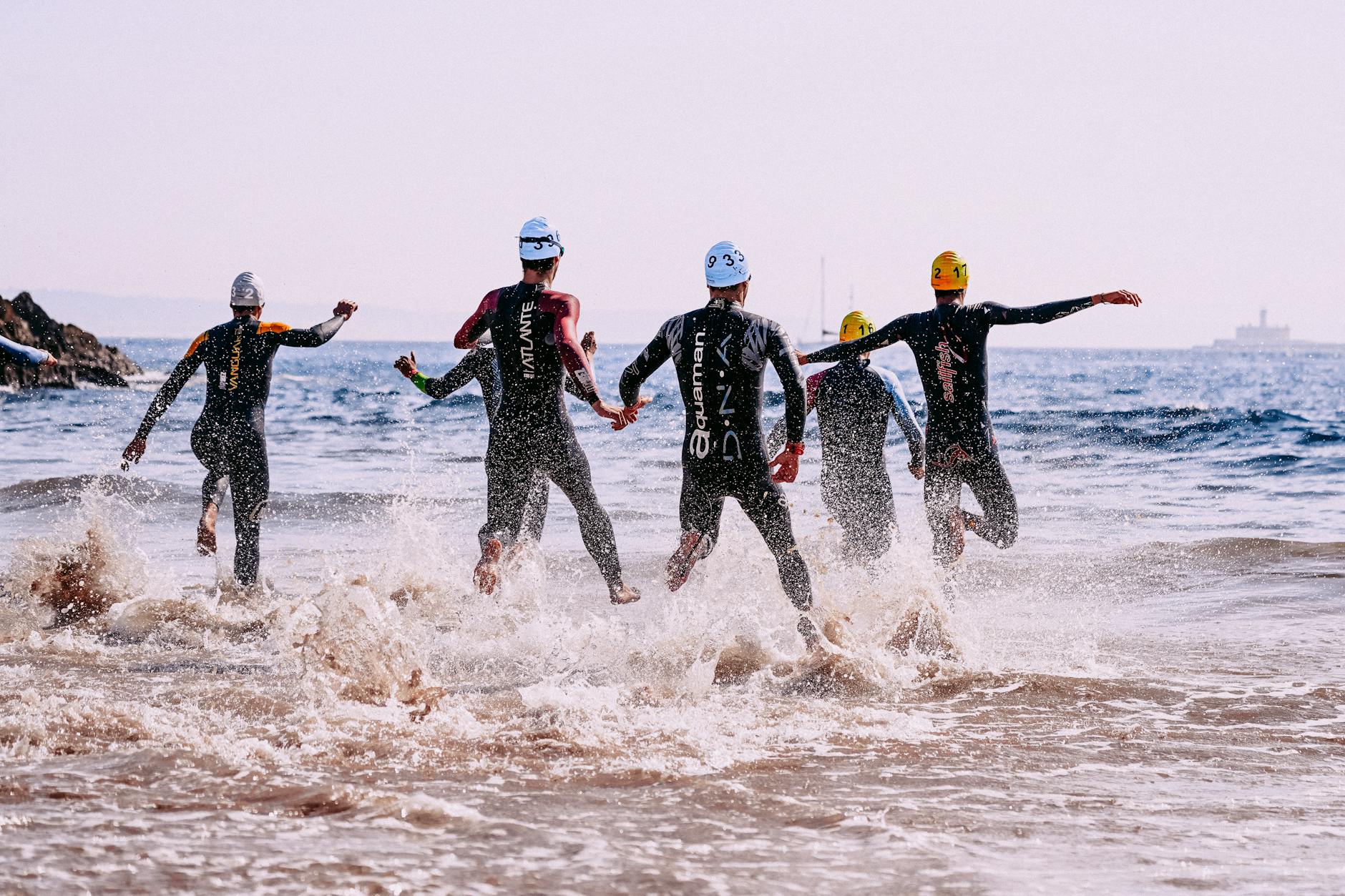 anonymous sportspeople running into sea in daytime