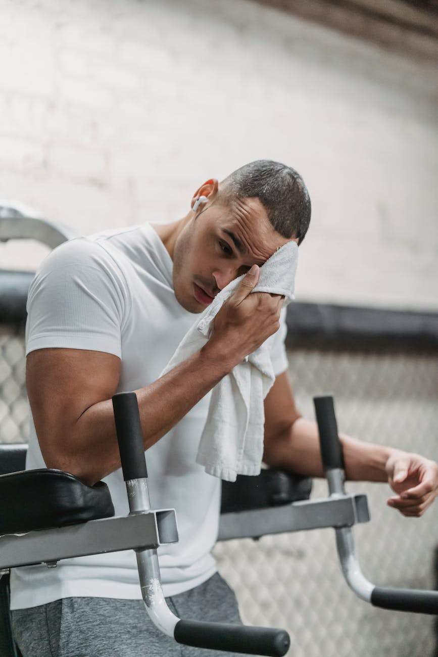 strong black man wiping forehead with towel in gym